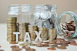 TAX text with golden coin growing money stairs or stack and glass jar on wooden table. business, investment, retirement planning,