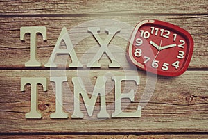 Tax Time alphabet with alarm clock on wooden background