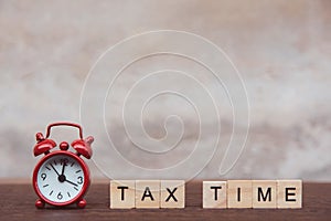 Tax time with Alphabet wooden block cube and Red alarm clock On table dark plank wooden background with copy space