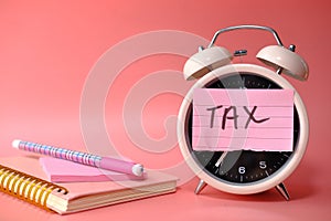 Tax time post-it on alarm clock on pink background.