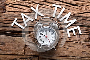Tax Time Text By Alarm Clock On Wooden Table