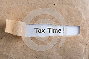 Tax Time words written on white paper at brown torn envelop