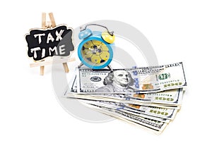 TAX TIME written on chalkboard with money and alarm clock on white background