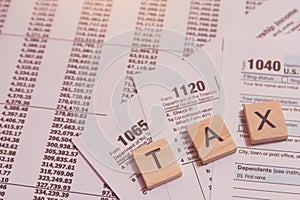 Tax with wooden alphabet blocks, calculator, pen on 1040 tax form backgrounda