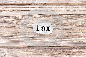 Tax of the word on paper. concept. Words of Tax on a wooden background