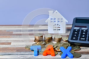 TAX word on wooden home and stack money coins concept