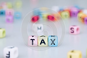 TAX word written on colorful cube with bokeh cube word block background