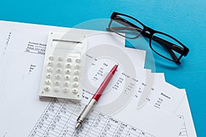 Taxes calculation concept. Financial documents, calculator, glasses on blue background