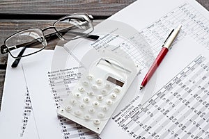 Taxes calculation concept. Financial documents, calculator, glasses on dark wooden background