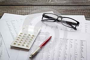 Taxes calculation concept. Financial documents, calculator, glasses on dark wooden background