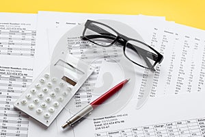 Taxes calculation concept. Financial documents, calculator, glasses on yellow background