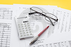 Taxes calculation concept. Financial documents, calculator, glasses on yellow background