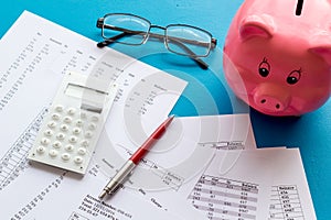 Taxes calculation concept. Financial documents, piggy bank, calculator on blue background