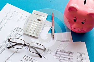 Taxes calculation concept. Financial documents, piggy bank, calculator on blue background