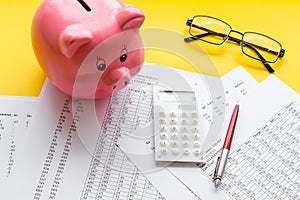 Taxes calculation concept. Financial documents, piggy bank, calculator on yellow background