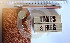 Taxes and fees Text on the wooden blocks, wallet and coins. Business concept