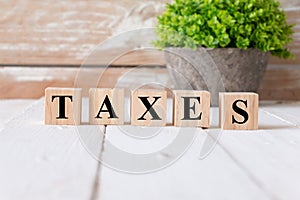 TAXES word. Alphabets written on wooden background