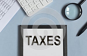 Taxes word on paper, reminder. Taxation concept, accounting and business