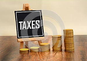 Taxes written on chalk board with golden stack of coins