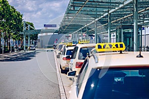 Taxi cabs waiting for passengers. Yellow taxi sign on cab cars. Taxi cars waiting arrival passengers in front of Airport Gate.