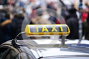 Taxi car in town centre crowded with pedestrians