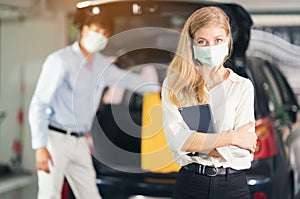 The taxi driver in medical mask putting yellow suitcases of women in the trunk of a car. People`s lifestyles and transportation
