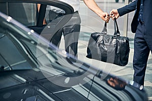 Taxi driver passing a duffel bag to a passenger