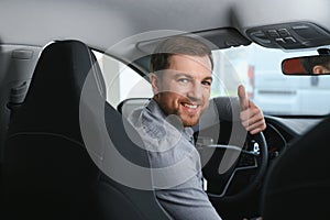 Taxi driver smiling while turning over to the backseat looking talking with clients. Successful businessman husband