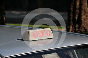 Taxi light sign or cab sign in drab white and red color with white text on the car roof at the street blurred background