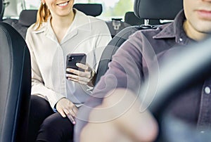 Taxi or rideshare car passenger using phone to pay for cab ride. Mobile payment, tip or review. Happy customer and driver.