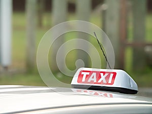 Taxi sign and aerial mounted ontop of a car with a reflection in