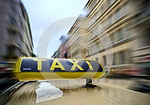 A taxi sign on a car with a lot of motion blur on the city background due to high speed