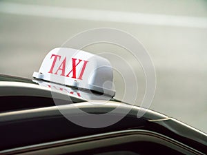 Taxi sign mounted ontop of a black car with a reflection in the