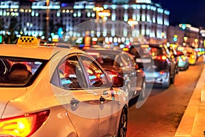 Taxi in traffic jam on the background of the lights of the night city and bokeh