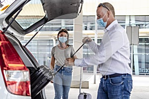 A taxi/Uber driver helping a passenger with her luggage at the airport