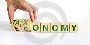 Taxonomy or economy symbol. Businessman turns cubes, changes the word economy to taxonomy. Beautiful white table, white background