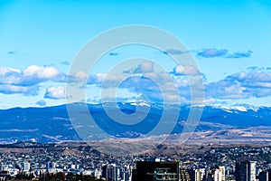 Tbilisi cityscape with snowy mountains and puffy clouds