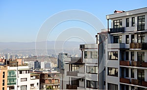 Tbilisi cityscape with snowy mountains and puffy clouds