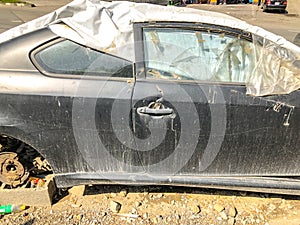 TBILISI, GEORGIA - - MAY 17, 2018: An old broken car covered with tarpaulin with a tire on the bonnet parked at the road