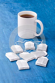 Tea bag and cup on the blue background.