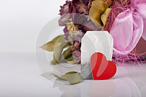 Tea bag with heart tag on floral background