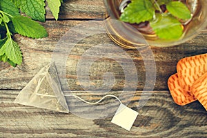 Tea bag, mint, cookie and cup of tea.