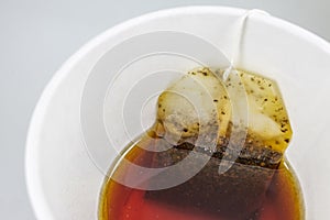Tea bag in paper cup and hot water