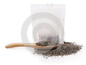 Tea bags and spoon with dry leaves on white background