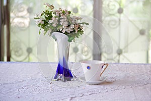 Tea in a beautiful cup and a bouquet from hawthorn branches