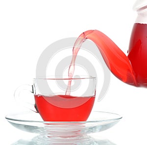 Tea being poured into glass tea cup isolated