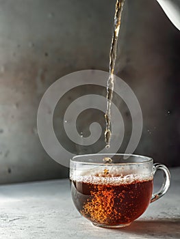 Tea being poured into glass tea cup with steam