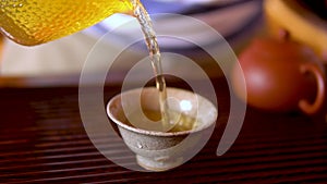 Tea being poured into traditional Chinese tea cup. hot drink.
