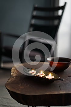 Tea candles burn in a candlestick on a sofa table against the background of a rocking chair