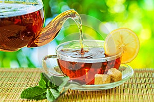 Tea ceremony, pouring tea from a teapot into a tea cup on a background of beautiful nature bokeh